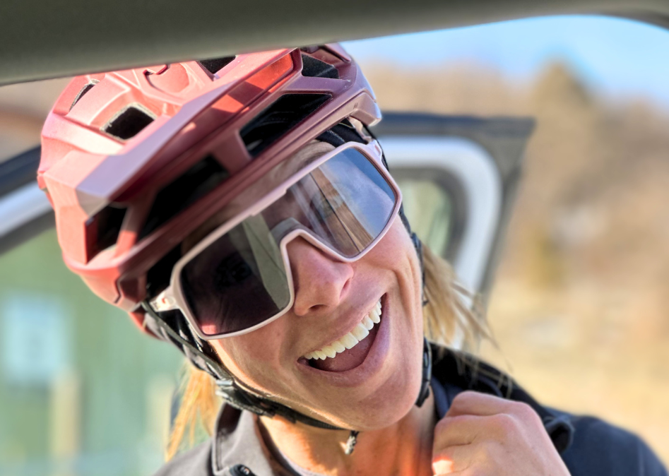 Person wearing a red helmet and sunglasses, smiling inside a vehicle.