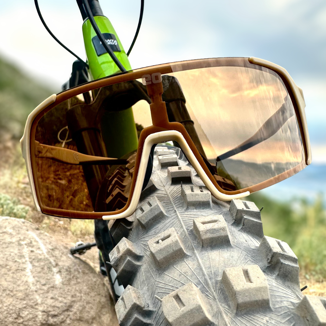 Eastern Outer brown lens photochromic Sunglasses on a mountain bike tire against a natural background