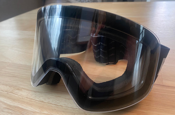 Clear lens attached to ski and snow goggles frame